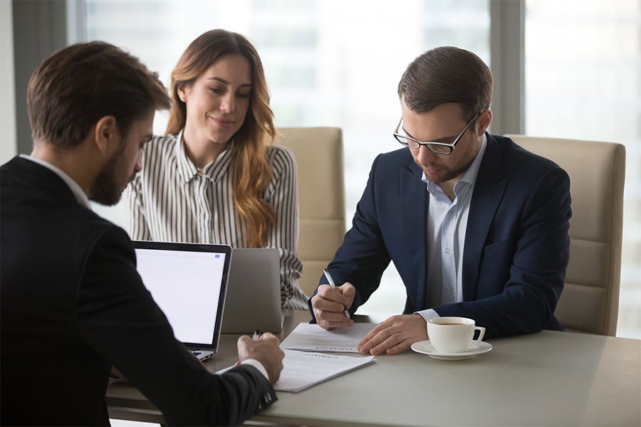A couple, inside an agent office, signing some papers